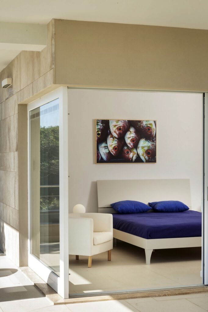 bed next to a large glass window opening on a garden